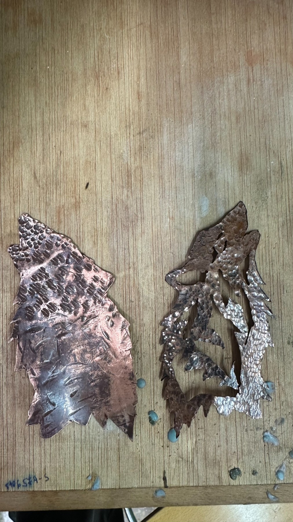 Dos siluetas de cobre caladas y texturizadas sobre la mesa de trabajo