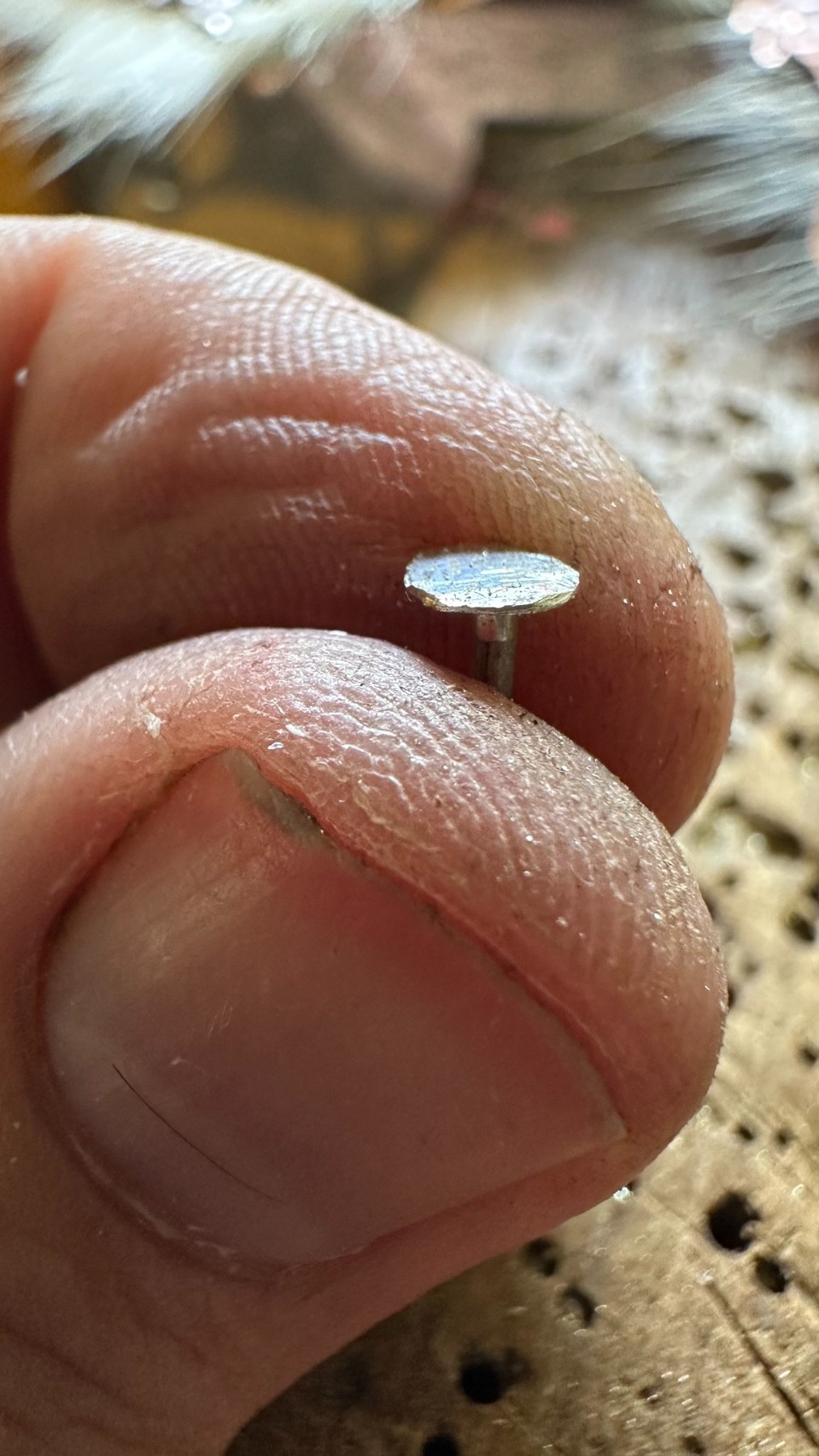 Un pequeño remache sostenido entre los dedos durante su fabricación